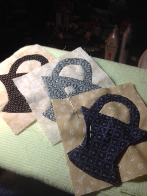 Fabric cut into basket-shaped pieces in various patterns, pinned together on a light green surface, crafty and quiet mood